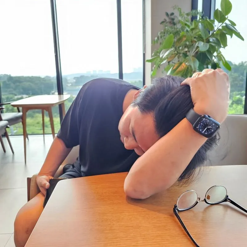 책상에 엎드려 머리를 감싸 쥔 모습